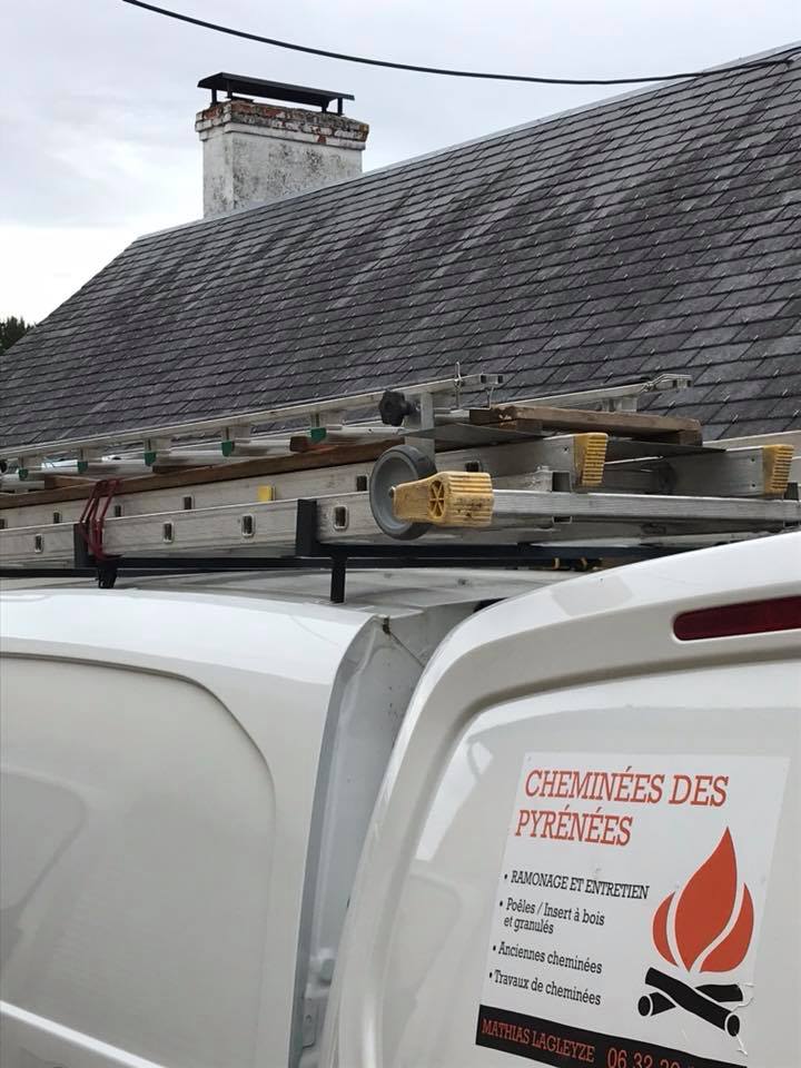 Camionnette Cheminées des Pyrénées à Séméac avec échelles et logo près d'une cheminée en briques blanches,